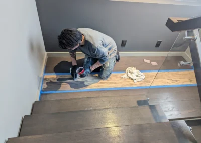 Staircase in the process of having its wood refinished and stained by FHG Contracting