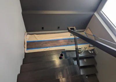 Staircase in the process of having its wood refinished and stained by FHG Contracting