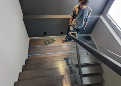Staircase in the process of having its wood refinished and stained by FHG Contracting