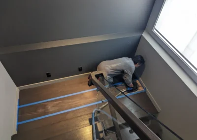 Staircase in the process of having its wood refinished and stained by FHG Contracting