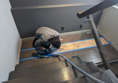 Staircase in the process of having its wood refinished and stained by FHG Contracting